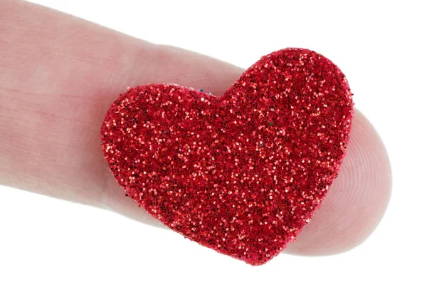 A small red paper heart is strewn with sparkles and lies on a fi — Stock Photo, Image