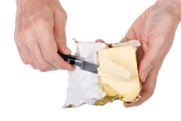 Old  poor senior  man cuts a stick of yellow butter with a sharp — Stock Photo, Image