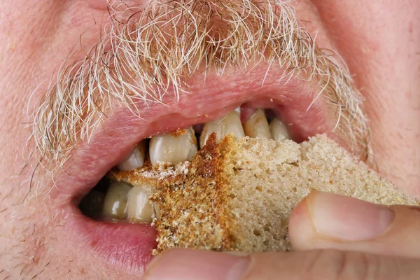 年配の老人は黄色い歯でパンを噛む — ストック写真