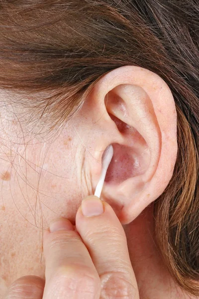 Old elderly senior woman cleans her ear with a cotton swab — Stock Photo, Image