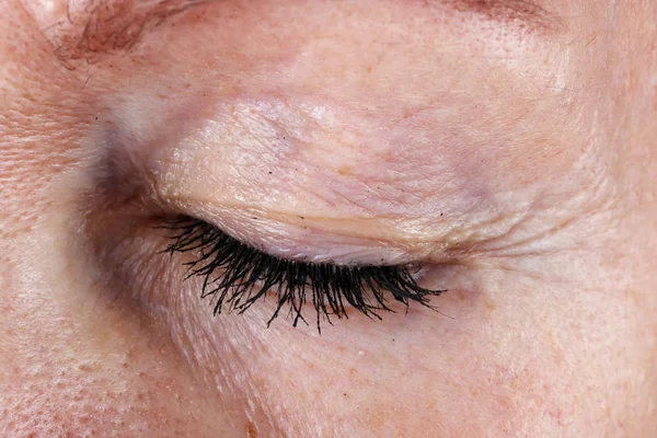 Closed  eye and eyelashes with lumps of black ink mascara from a — Stock Photo, Image