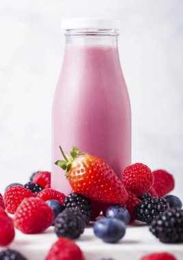 Taze yaz meyve güler yüzlü ahşap arka plan üzerinde cam şişe. Strwberries ve raspberies yaban mersini ve böğürtlen ile.