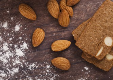 Ahşap arka plan üzerinde çiğ badem ile ev yapımı badem bisküvi kurabiye