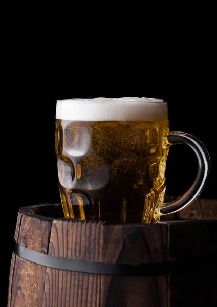 stock image Cold glass of craft beer on old wooden barrel on black background