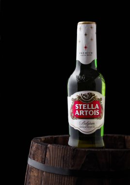 Londra, İngiltere - 06 Haziran 2018: Soğuk cam şişesini Stella Artois siyah arka plan üzerine eski ahşap varil üzerinde.