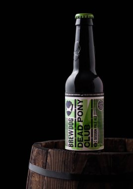 Londra, İngiltere - 06 Haziran 2018: Ölü Pony Club şişe soluk ale bira, siyah arka plan üzerine eski ahşap varil üzerinde Brewdog brewery.