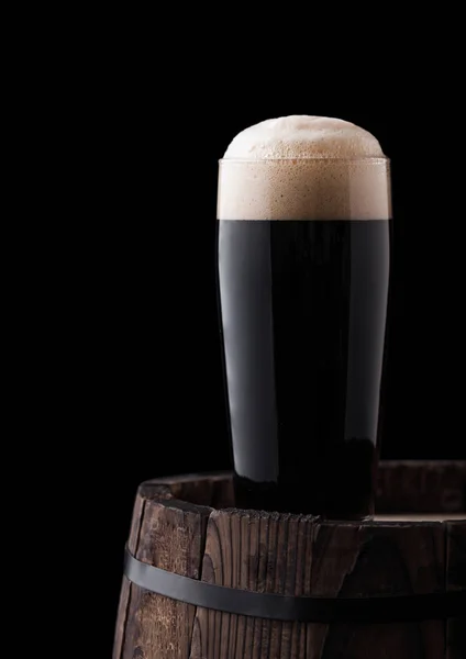 黒の背景に木製の樽型の黒スタウト ビールの冷たいガラス — ストック写真