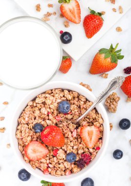 Kase çilek ve böğürtlen ve mermer tahta üzerinde süt ile sağlıklı tahıl granola