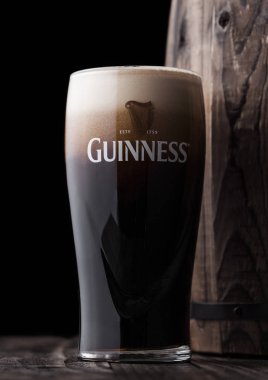 Londra, İngiltere - 27 Nisan 2018: Orijinal bardak Guinness fıçı şişman bira eski ahşap varil yanında. Guinness bira Dublin, İrlanda 1759 yılından bu yana üretilen.