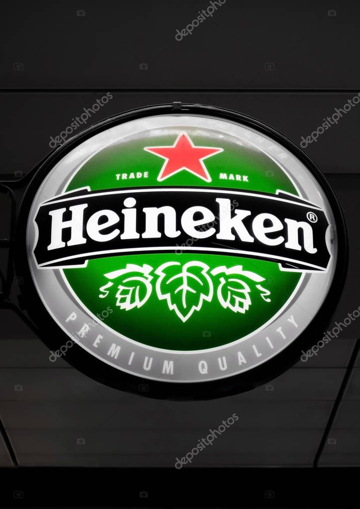 AMSTERDAM, NETHERLANDS - JULY 18, 2018: Round billboard of Heineken lager beer hanging next to pub on dark background.