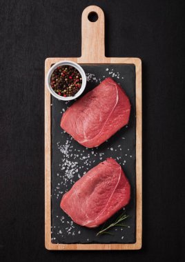 Taze çiğ Dana biftek etli biber siyah arka plan üzerine taş mutfak gemide