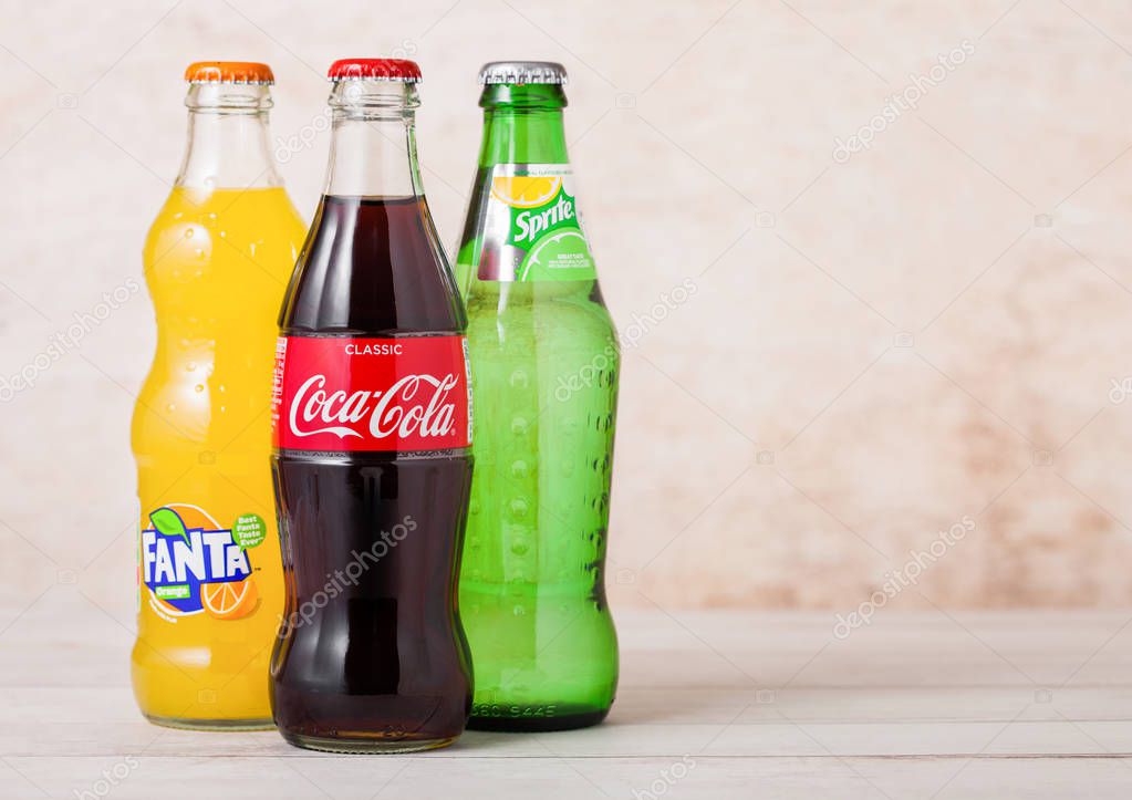 LONDON, UK - AUGUST 03, 2018: Glass bottles of Coca Cola and Fanta and Sprite soft drink on wood. Most popular drinks in the world.