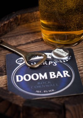 Londra, İngiltere - 10 Ağustos 2018: Doom bar şişe üst ve açacağı ve bardak bira üzerine ahşap varil bira altlığı.