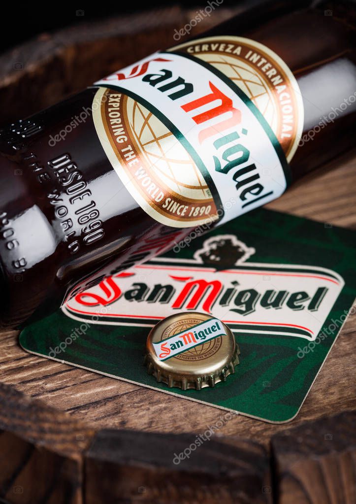 LONDON, UK - AUGUST 10, 2018: San Miguel beer coaster with bottle top and bottle on wood barrel.