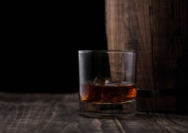 Bir bardak viski ahşap varil yanında buz küpleri ile. Konyak ve brendi içmek