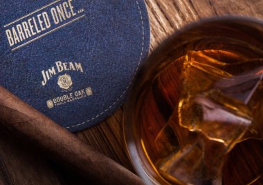 Londra, İngiltere - 04 Eylül 2018: Cam Jim Beam burbon viski ile orijinal coaster ve puro ahşap tahta üzerinde.