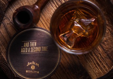 Londra, İngiltere - 04 Eylül 2018: Cam Jim Beam burbon viski orijinal coaster ve ahşap tahta üzerinde vintage yasaktır boru ile.