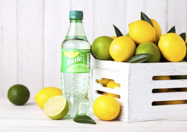 Londra, İngiltere - 03 Eylül 2018: Limon ve limes ahşap zemin üzerine Sprite şişe içki. Sprite limon benzeri aromalı içecek Coca Cola Company tarafından üretilen olduğunu.