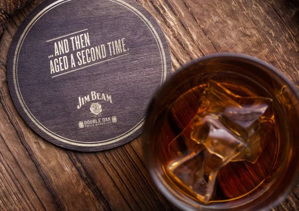 Londra, İngiltere - 04 Eylül 2018: Cam Jim Beam burbon viski orijinal ahşap tahta altlığı ile.