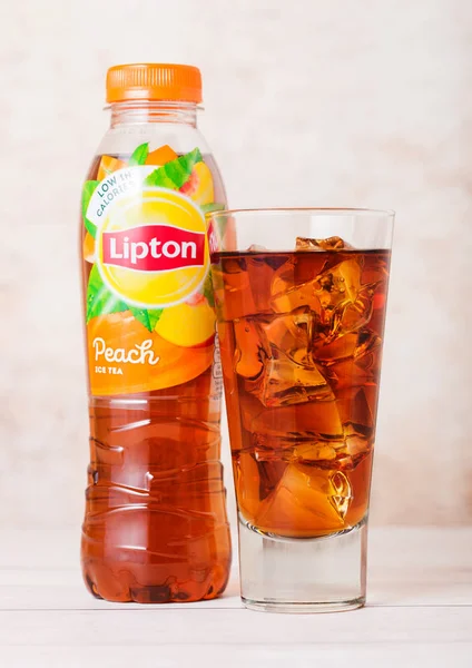 LONDON, İngiltere - SEPTEMBER 03, 2018: Ahşap üzerine şeftali aromalı buzlu Lipton Ice Tea ile plastik şişe ve cam.