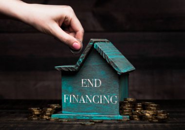 Ahşap ev modeli ile yanında içinde kavramsal metin ve koyar madeni para ile bozuk paralar. Sonunda finansman