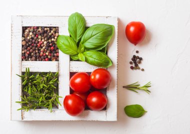 Organik kiraz domates fesleğen ve biber ve biberiye taş zemin üzerine beyaz ahşap kutusunda.