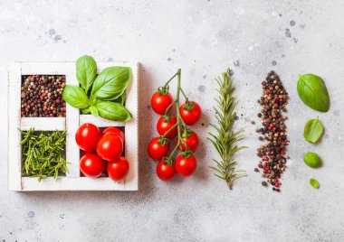 Organik kiraz domates fesleğen ve biber ve biberiye taş zemin üzerine beyaz ahşap kutusunda.