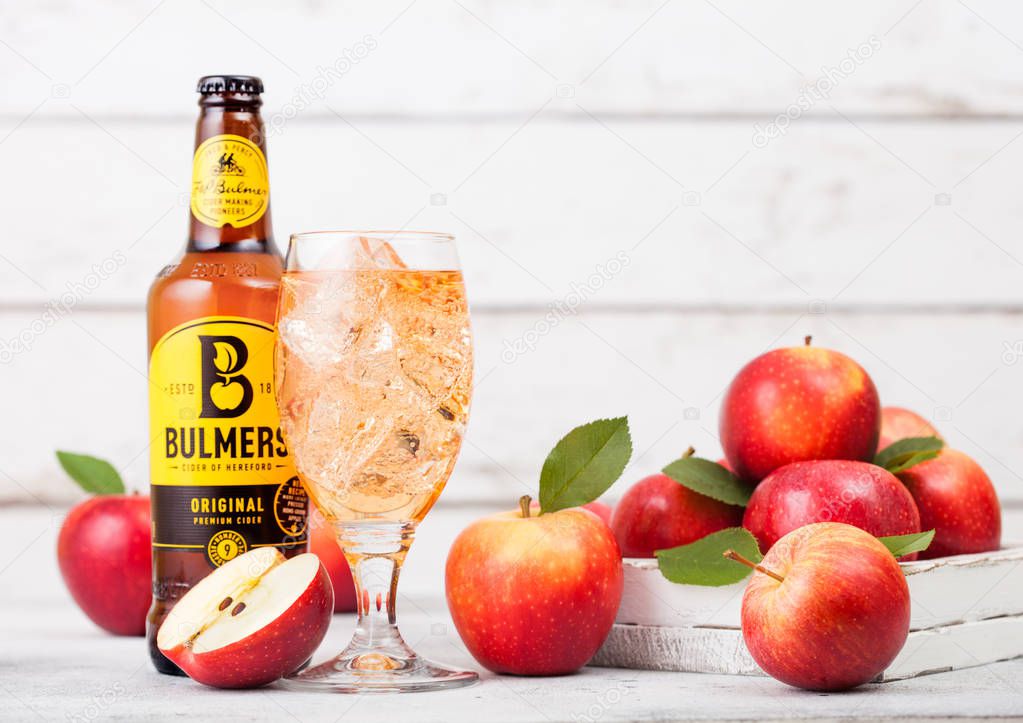 LONDON, UK - SEPTEMBER 13, 2018: Bottle of Bulmers Original Cider and glass of ice cubes with fresh apples on wood background.