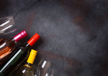 Gözlüklü taş mutfak masa arka plan üzerinde kırmızı beyaz ve pembe gül şarap şişeleri. Üstten görünüm