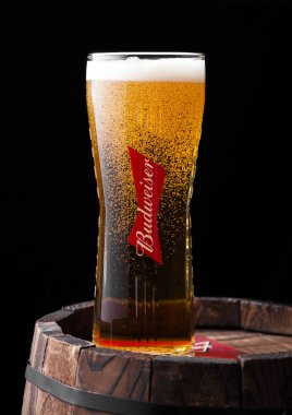 LONDON, UK - 27 Nisan 2018: Orijinal Budweiser bardağı çiy ve baloncuklarla dolu eski ahşap fıçının üzerinde, Amerikan birası ilk kez 1876 'da tanıtıldı..
