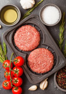 Plastik tepsi ile baharat ve otlar ile çiğ kıyılmış ev yapımı ızgara sığır eti hamburger. Üstten görünüm.