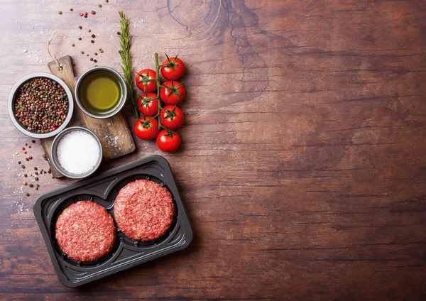 Plastik tepsi ile baharat ve otlar ile çiğ kıyılmış ev yapımı ızgara sığır eti hamburger. Üstten görünüm ve metin için yer.