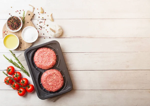 Plastik tepsi ile baharat ve otlar ile çiğ kıyılmış ev yapımı ızgara sığır eti hamburger. Üstten görünüm ve metin için yer.