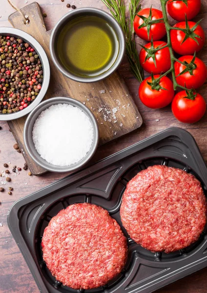 Plastik tepsi ile baharat ve otlar ile çiğ kıyılmış ev yapımı ızgara sığır eti hamburger. Üstten görünüm ve metin için yer.
