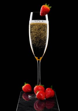 Zarif bir bardak sarı şampanya üzerinde çilek ve siyah mermer tahtada taze böğürtlen..