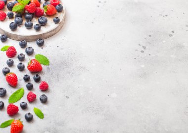 Yuvarlak vintage tahta zemin üzerine taze ham organik çilek. Metin için yer. Çilek, ahududu, yaban mersini ve nane yaprağı