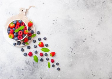 Taze ham organik çilek beyaz seramik kase üzerinde izole ahşap tahta yuvarlak. Metin için yer. Çilek, ahududu, yaban mersini ve nane yaprağı