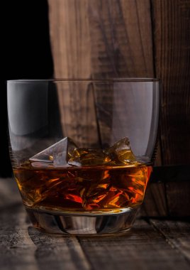 Bir bardak viski ahşap varil yanında buz küpleri ile. Konyak ve brendi içmek