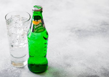 LONDON, UK - SEPTEMBER 28, 2018: Glass and bottle of Sprite soda drink with ice cubes and bubbles on stone kitchen table background. clipart