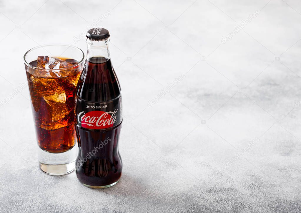 LONDON, UK - SEPTEMBER 28, 2018: Glass and bottle of Coca Cola Zero soda drink with ice cubes and bubbles on stone kitchen background.