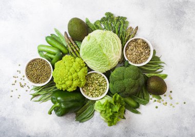 Çeşitli yeşil beyaz arka plan üzerinde ham organik sebze tonda. Avokado, lahana, brokoli, karnabahar ve salatalık ile kesilmiş ve gevşek mung fasulye, pak choi, biber ve marul