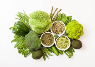 Çeşitli yeşil beyaz arka plan üzerinde ham organik sebze tonda. Avokado, lahana, brokoli, karnabahar ve salatalık ile kesilmiş ve gevşek mung fasulye, pak choi, biber ve marul