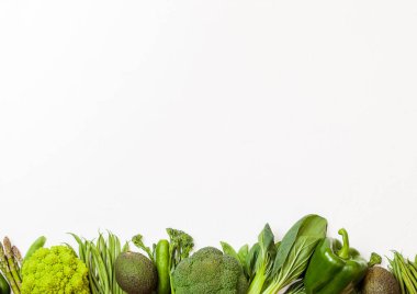 Çeşitli yeşil beyaz arka plan üzerinde ham organik sebze tonda. Avokado, lahana, brokoli, karnabahar ve salatalık ile kesilmiş ve gevşek mung fasulye, pak choi, biber ve marul