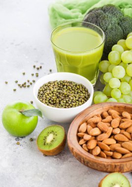 Bardak taze yüzlü suyu organik yeşil tonda meyve ve sebze taş mutfak masa arka plan üzerinde. Badem fındık ile kase.