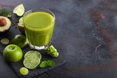 Bardak taze ham organik yeşil tonda meyve ve sebze taş tahta arka plan üzerinde. Avokado, limon, elma, kivi ve karnabahar ve brokoli ile üzüm