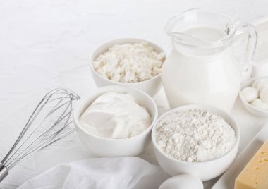 Beyaz arka plan üzerinde taze süt ürünleri. Cam kavanoz süt, kase, ekşi krema, peynir ve un ve mozzarella pişirme. Yumurta ve peynir. Çelik çırpıcı ve doğrayıcılı