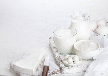 Beyaz masa artalanını vintage ahşap kutusunda taze süt ürünleri. Kavanoz ve bir bardak süt, kase ekşi krema ve peynir.