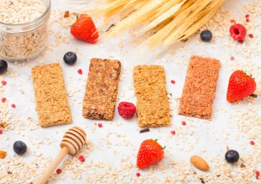Çilek tatlım kaşık ve yulaf mermer masa arka plan üzerinde kavanoz ile organik tahıl granola bar. Üstten görünüm. Çilek, ahududu ve badem fındık ile yaban mersini.