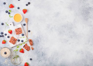 Çilek tatlım kaşık ve yulaf mermer zemin üzerine kavanoz ile eski Yönetim Kurulu ile organik tahıl granola bar. Çilek, ahududu ve nane yaprağı ile yaban mersini 