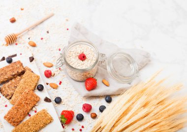 Organik tahıl granola bar tatlım kaşık ve mermer masa artalanını yulaf ve keten havluda kavanoz ile mermer gemide çilek ile.